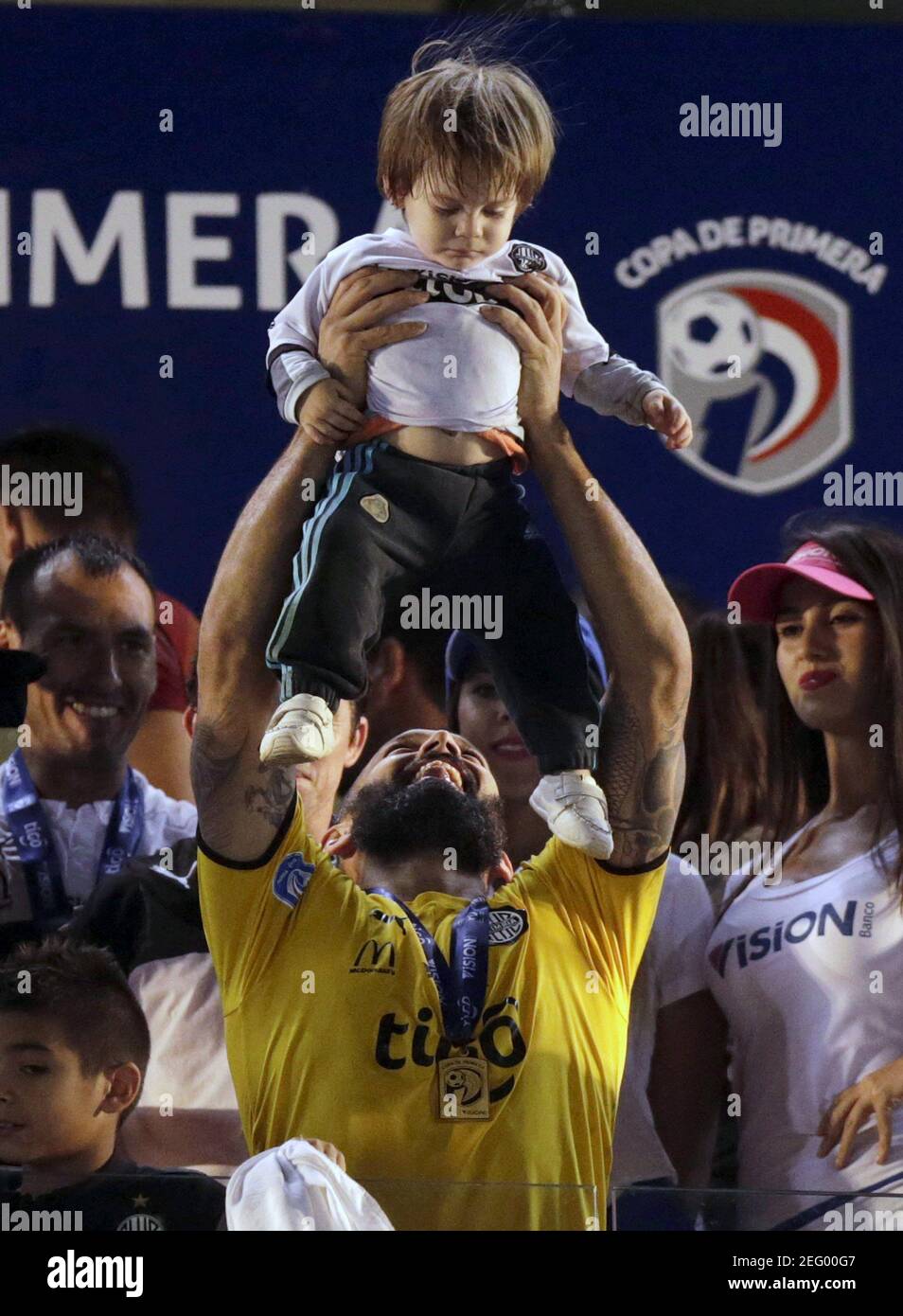 Olimpia's goalkeeper Diego Barreto (yellow) holds his son as he celebrates after winning the Paraguayan championship against Cerro Porteno at the Defensores del Chaco stadium in Asuncion December 9, 2015. REUTERS/Jorge Adorno   Picture Supplied by Action Images Stock Photo