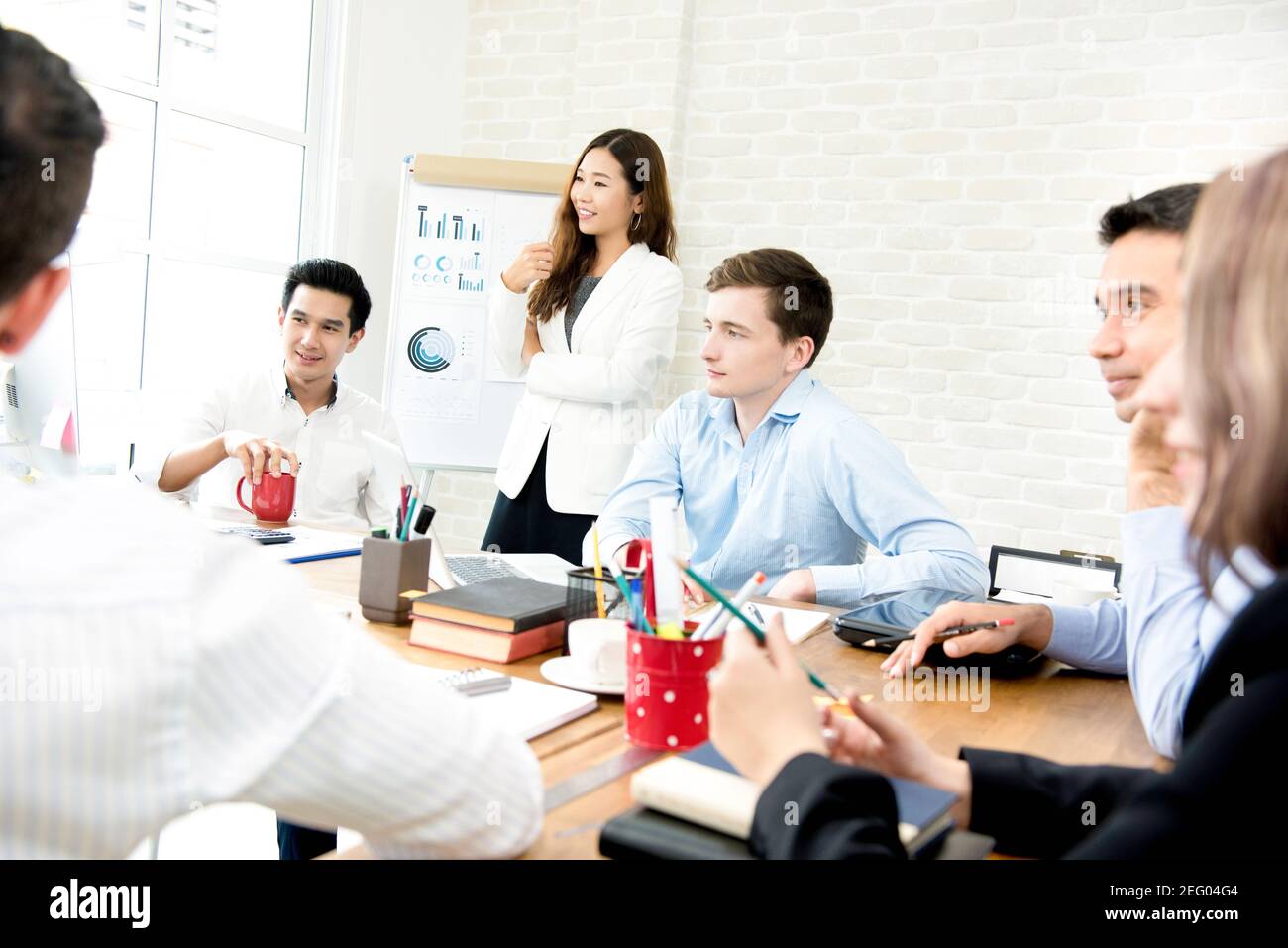 Young interracial business people listening to their colleague in the meeting - teamwork and brainstorming concepts Stock Photo