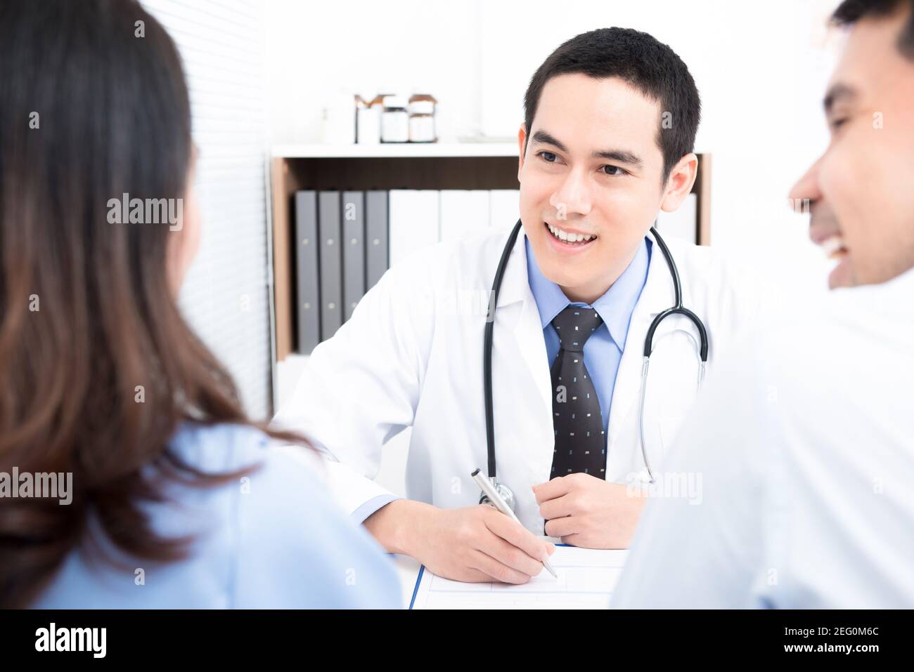 Doctor consulting with young couple patients - family and infertility consultation concepts Stock Photo