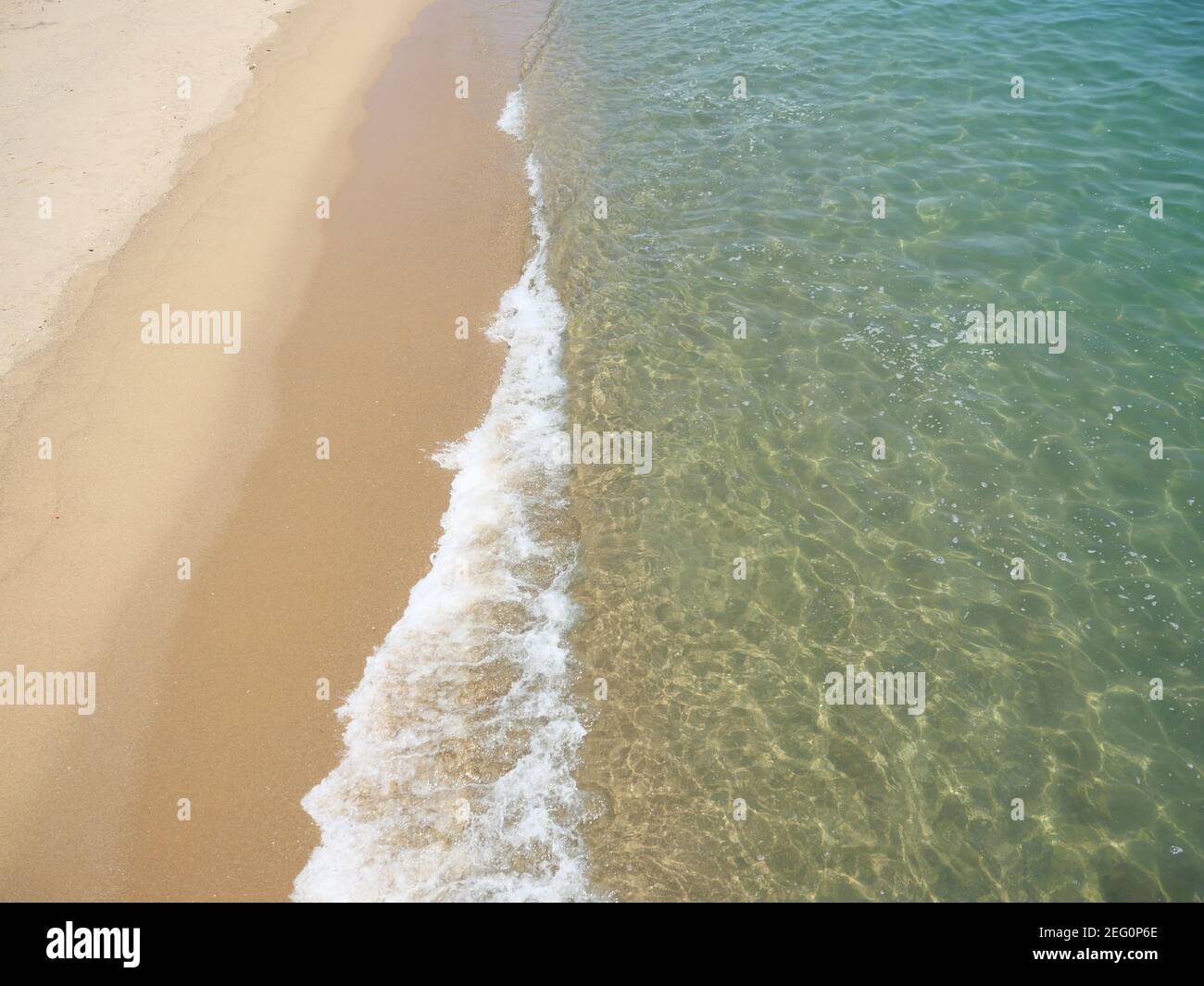 White bubble and green water of sea wave splashing on brown sand of the ...