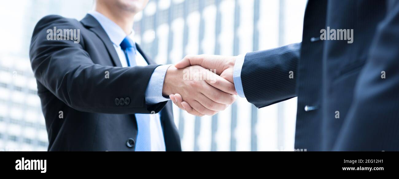 Businessmen making handshake in the city - business etiquette, congratulation, merger and acquisition concepts, panoramic banner Stock Photo