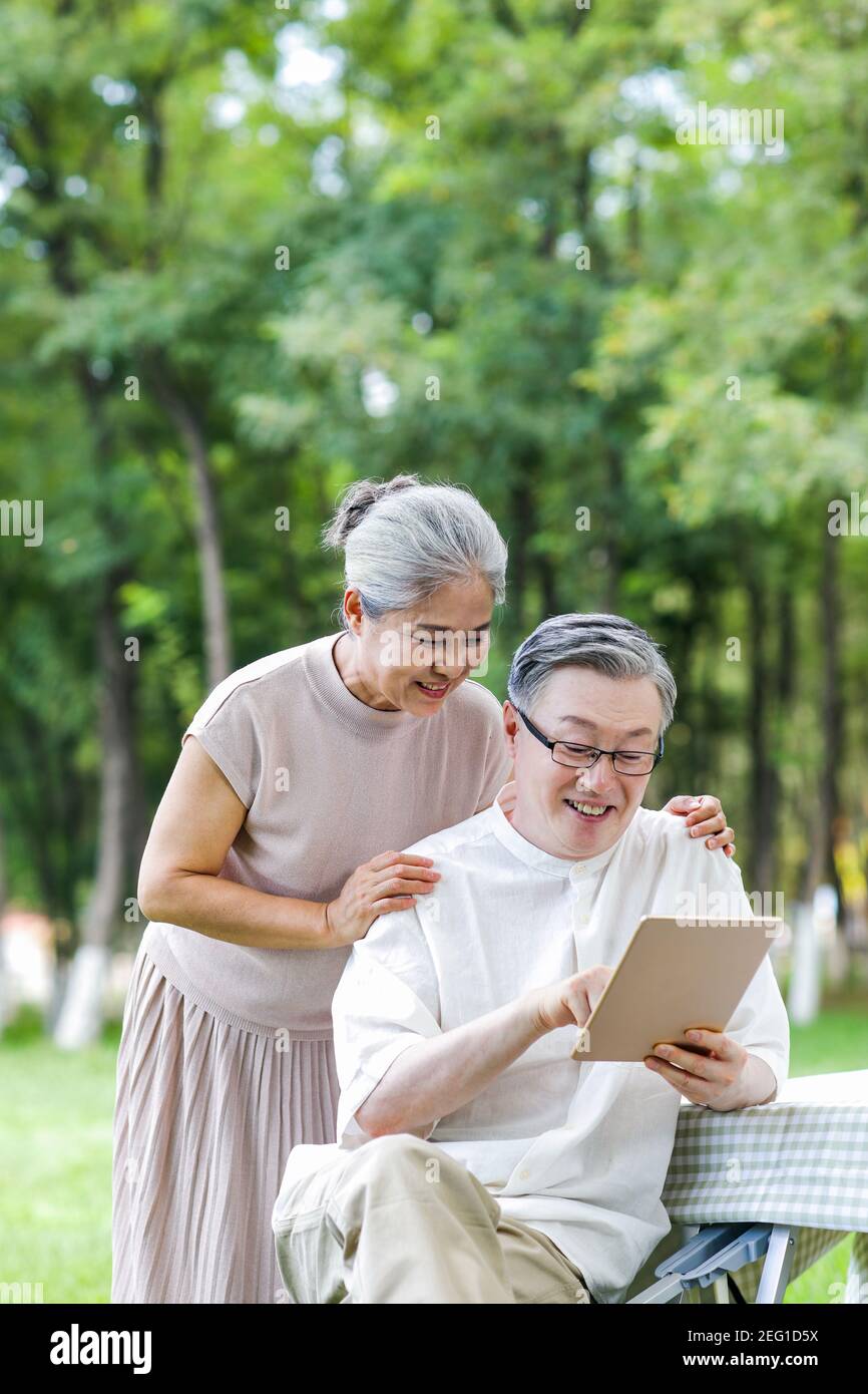 Happy elderly couples use tablet computers in the park Stock Photo