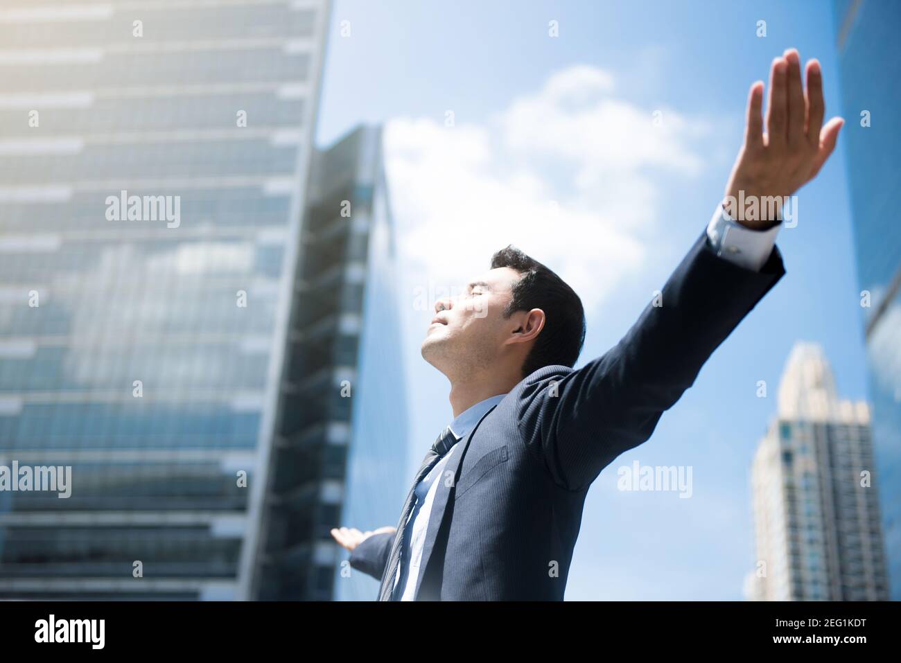 Happy businessman raising his arms, open palms, with face looking up ...