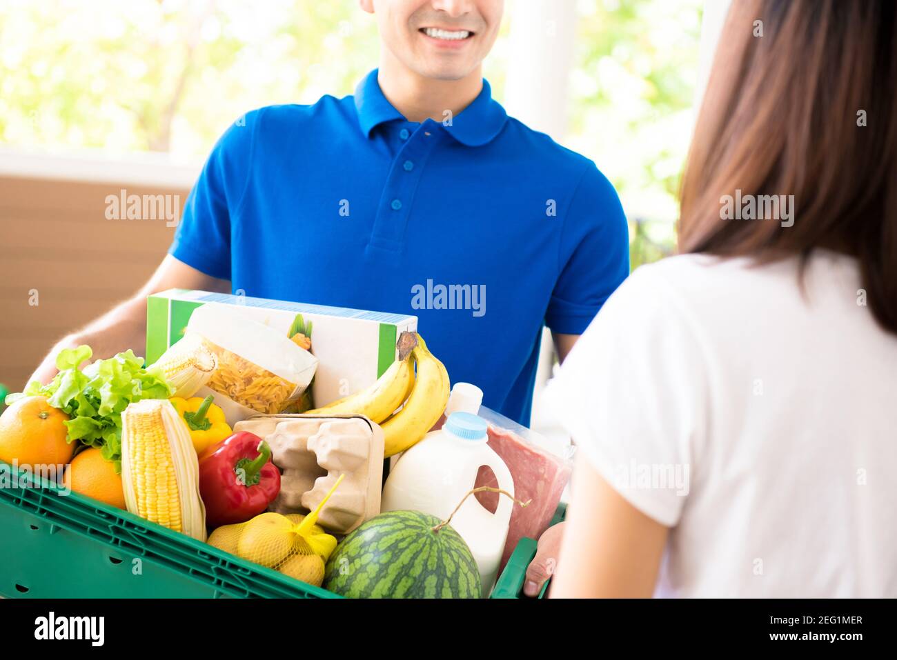 Delivery man delivering food to a woman at home - online grocery shopping service concept Stock Photo