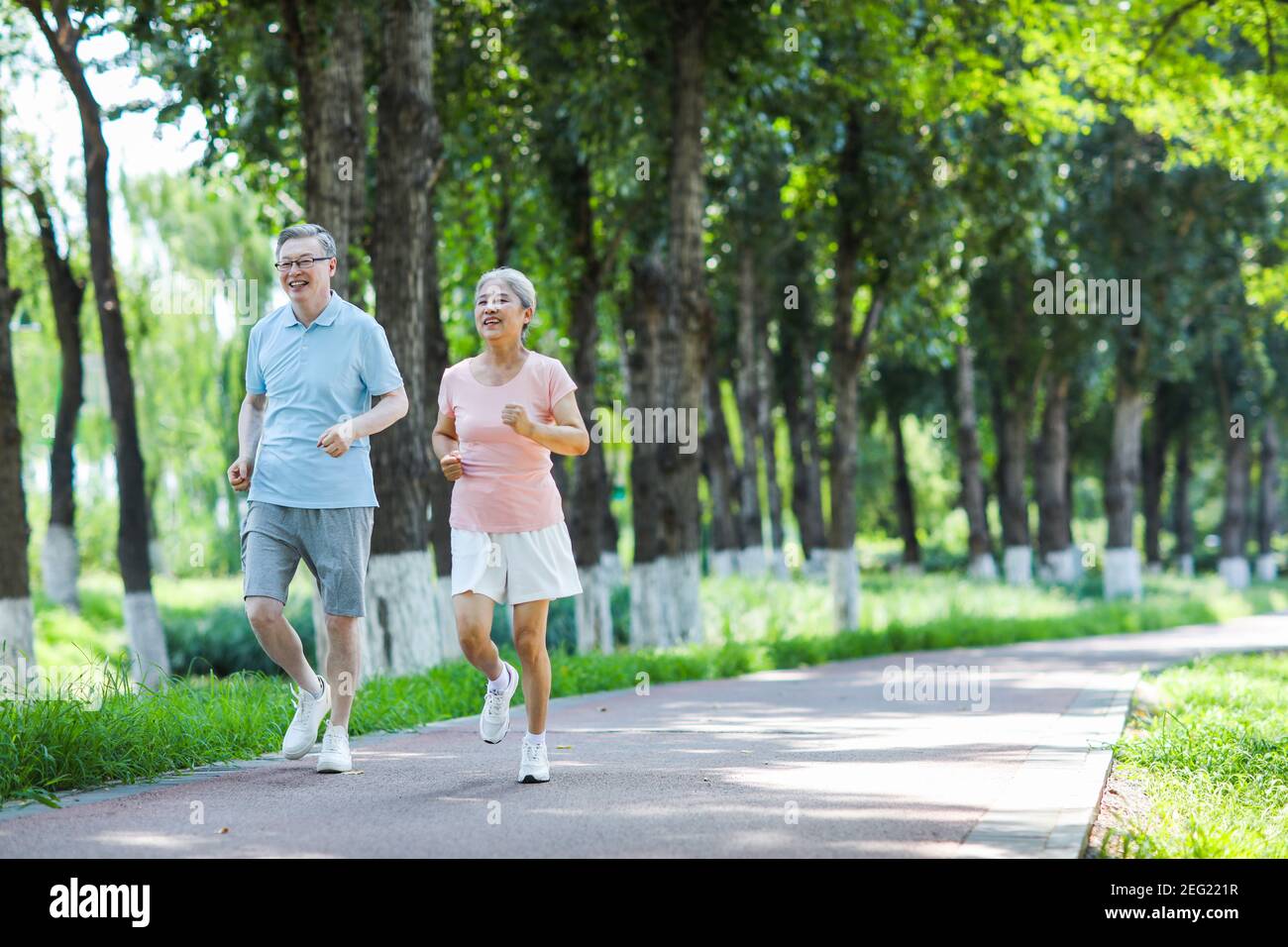 Old couple jogging in outdoor park smiling Stock Photo - Alamy