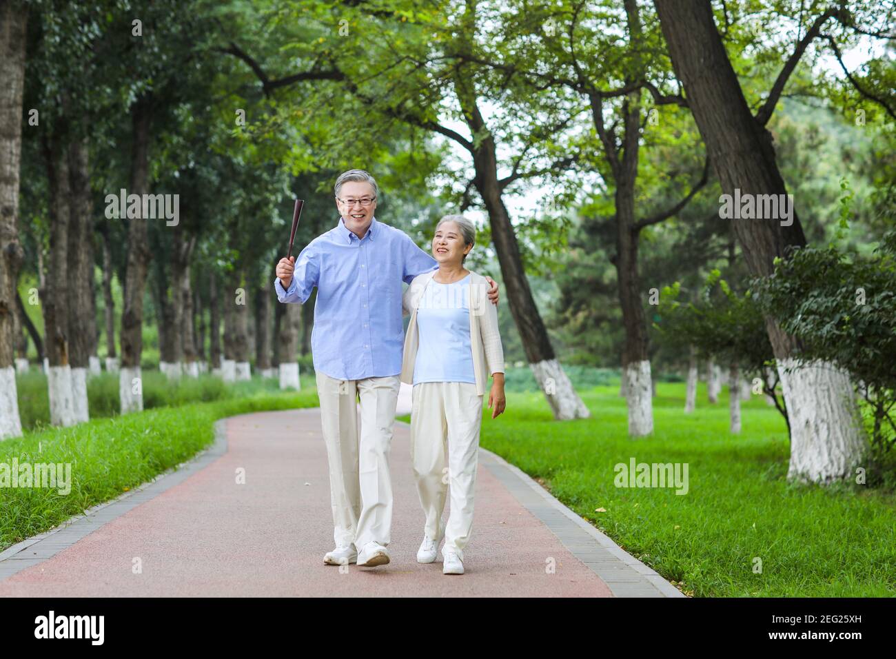 Happy old couple walking in the park Arms around shoulders Stock Photo ...
