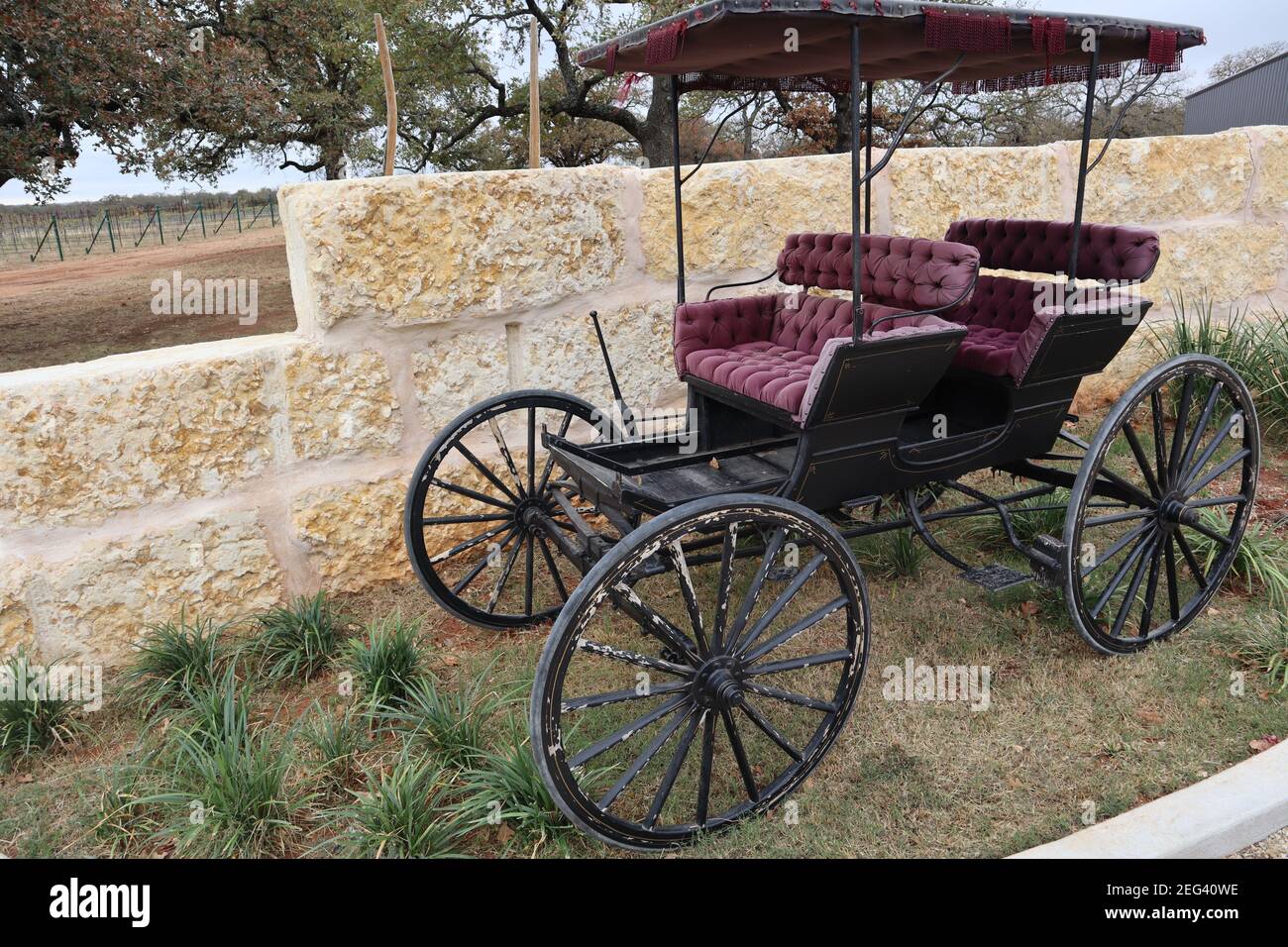 Shot of an old horse carriage phaeton in red and black colors in the background of a beige wall Stock Photo