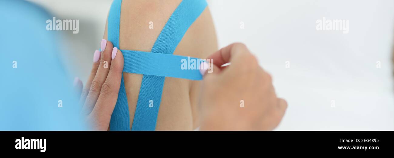 Hands of doctor sticking tape on knee of athlete closeup Stock Photo