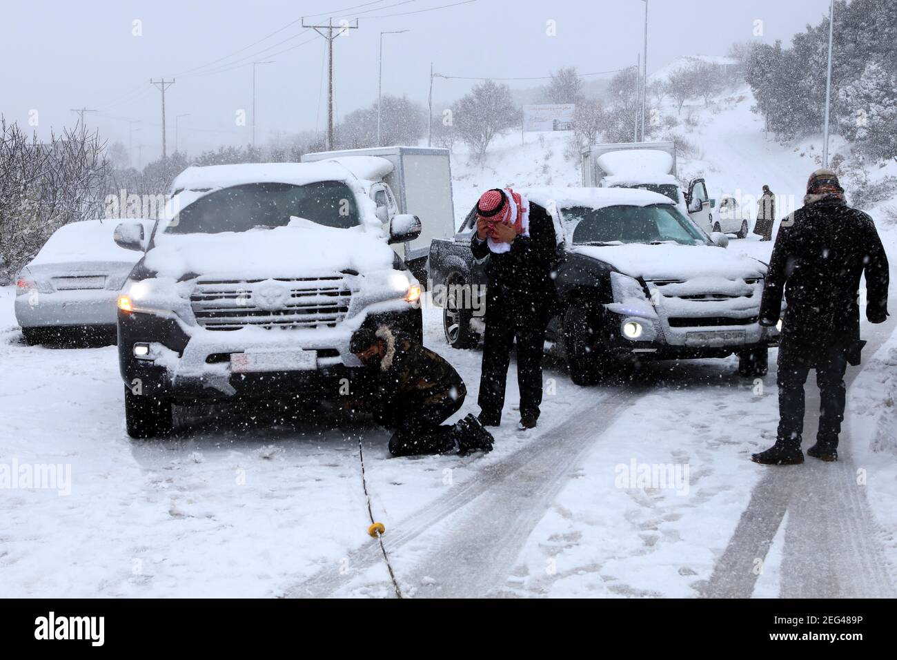 Ajloun, Jordan. 17th Feb, 2021. People check a car stuck in snow in Ajloun, Jordan, on Feb. 17, 2021. A snowstorm on Wednesday hit Jordan's mountainous areas accompanied by heavy winds and cold weather. Credit: Mohammad Abu Ghosh/Xinhua/Alamy Live News Stock Photo