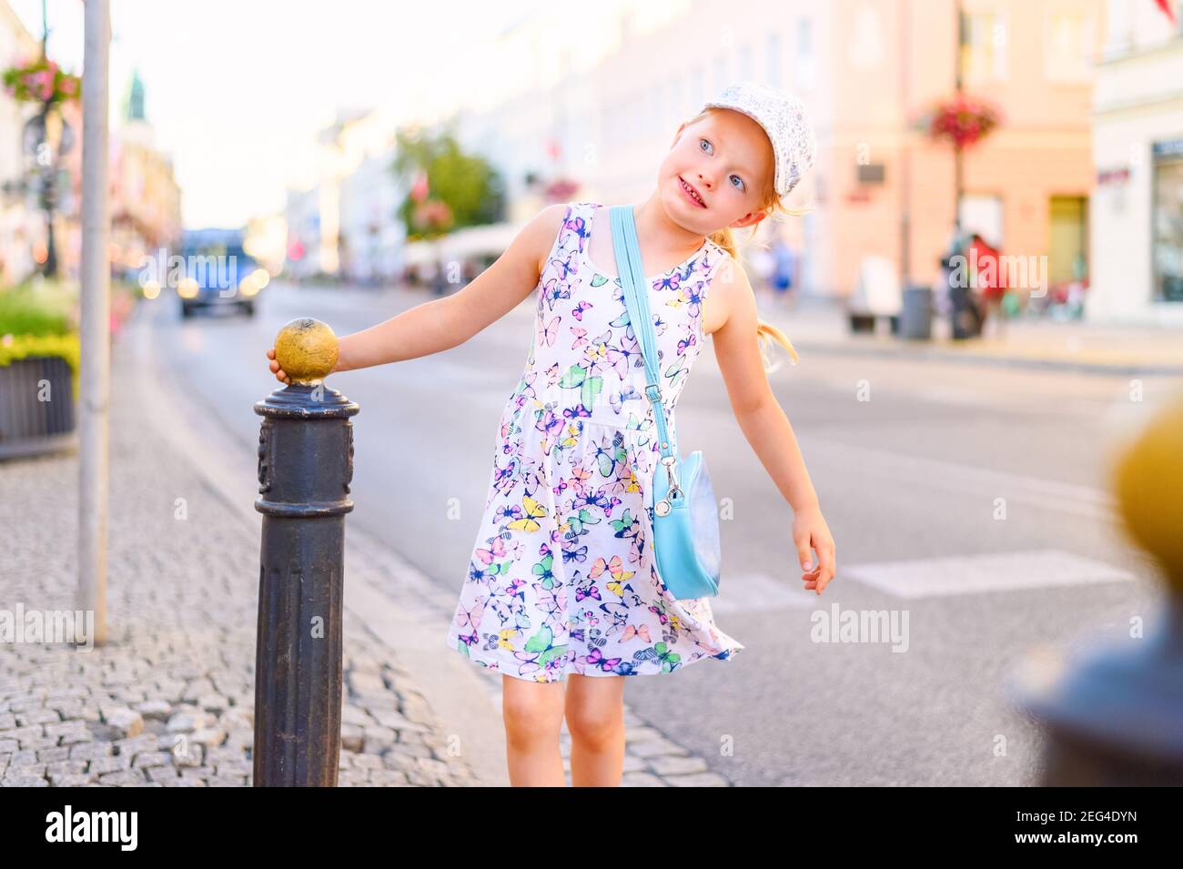 little girl in a dress walking and enjoying outdoor on a city street in a summer day Stock Photo