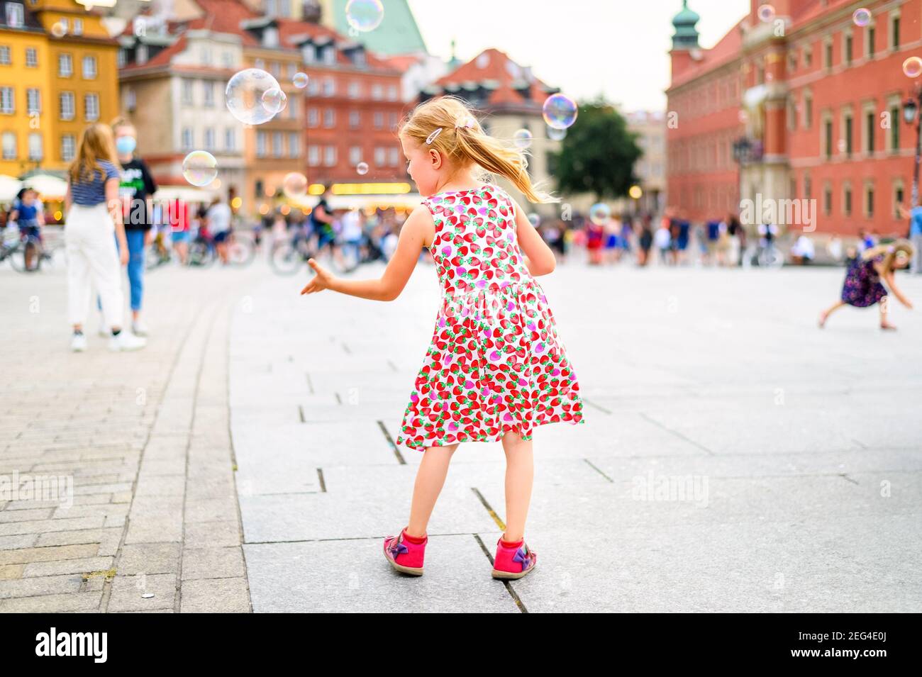 little girl playing with soap bubbles in a city center Stock Photo