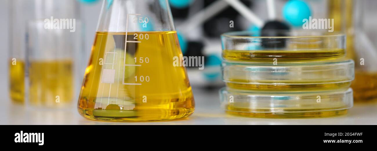 Glass test tubes with yellow viscous liquid stand on table in chemical