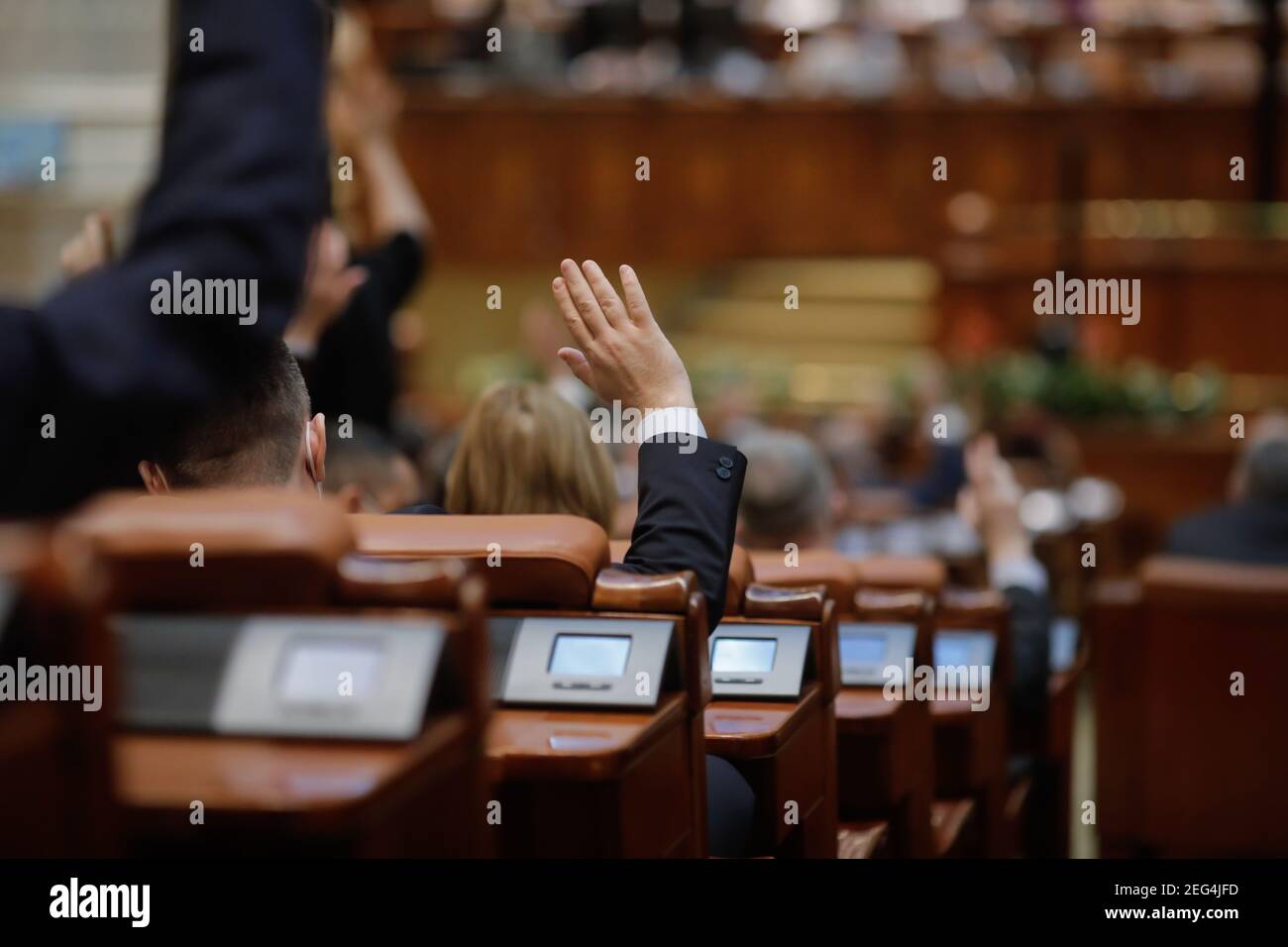 Bucharest, Romania - February 17, 2021: Shallow depth of field (selective focus) with details of Romanian MPs voting by raising their hands. Stock Photo