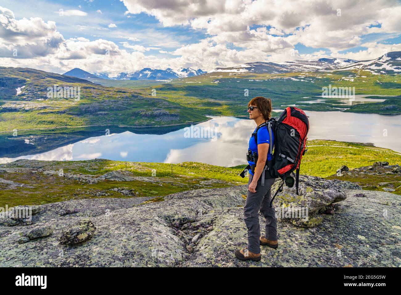 Woman on a mountain with a backpack watching the nice view with  mountains in the background, Stora sjöfallets nationalpark, Swedish Lapland, Sweden Stock Photo
