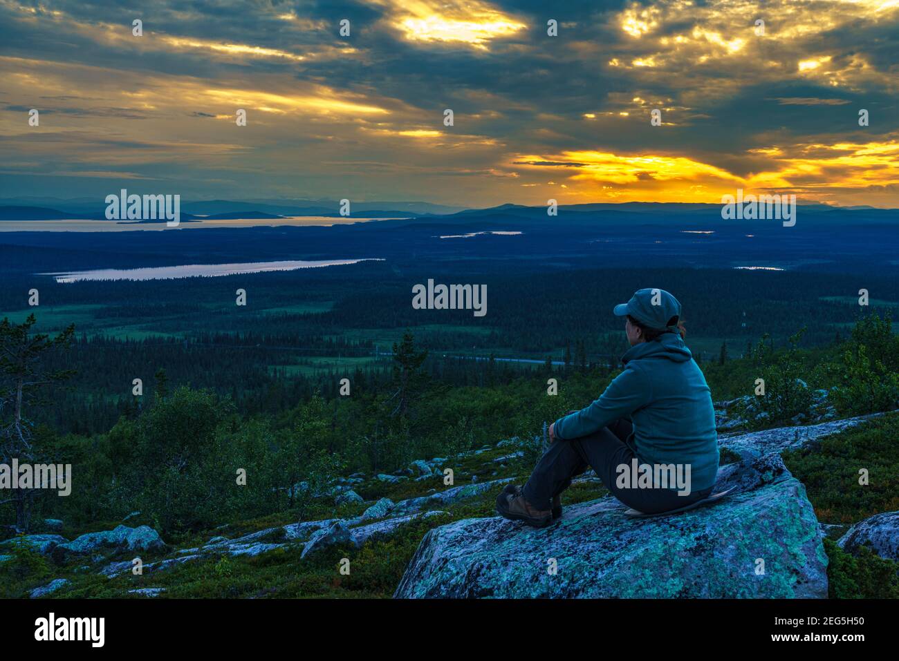 Woman enjoying the sunset, with colorfull sky and mountains in background, Gällivare county, Swedish Lapland, Sweden Stock Photo