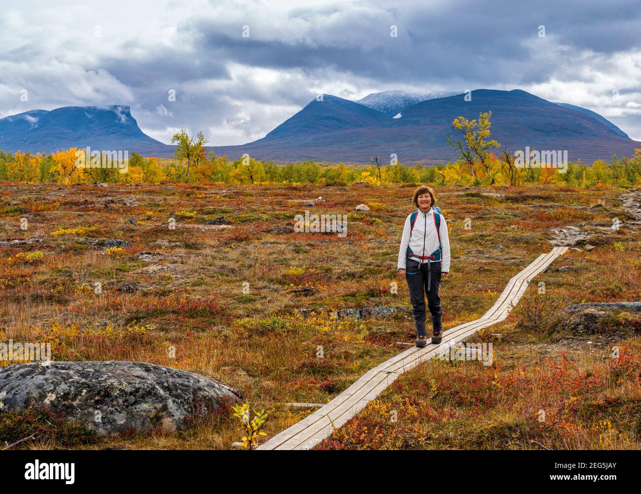 Woman hiking  with backpack in autumn season in Abisko nationalpark with Lapporten in background, Abisko, Swedish Lapland, Sweden Stock Photo