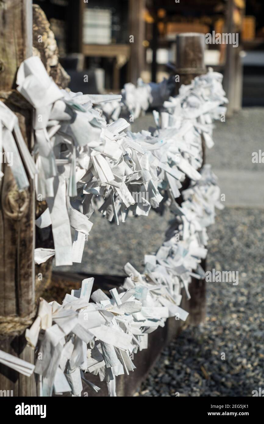 Close up detail of hundreds of Omikuji paper fotrune telling slips tied to string at a Shinto shrine in Kyoto Japan Stock Photo