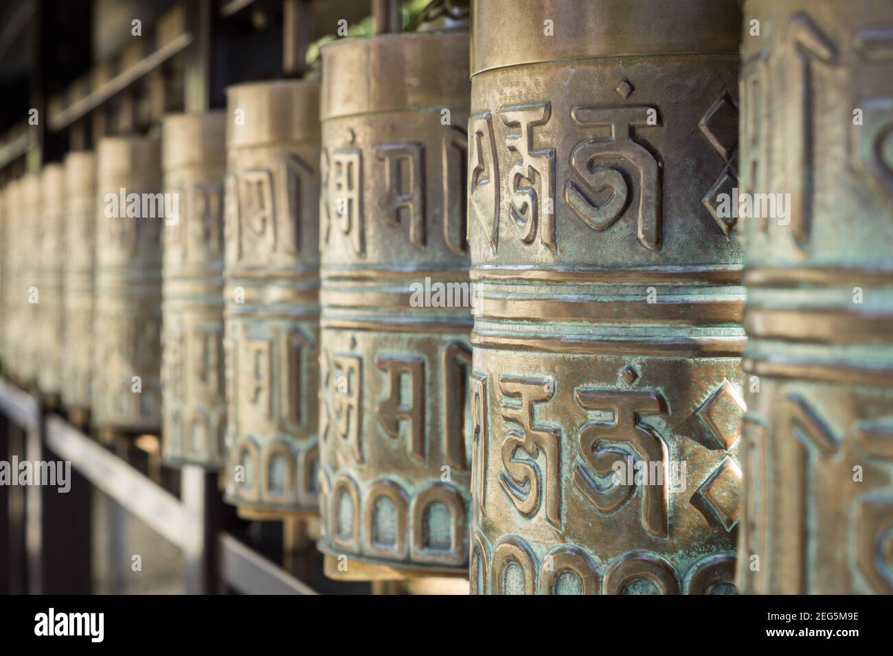 Close up detail of Sanskrit writing on bronze Tibetan style Buddhist prayer wheels at Kodaiji temple in Kyoto, Japan Stock Photo