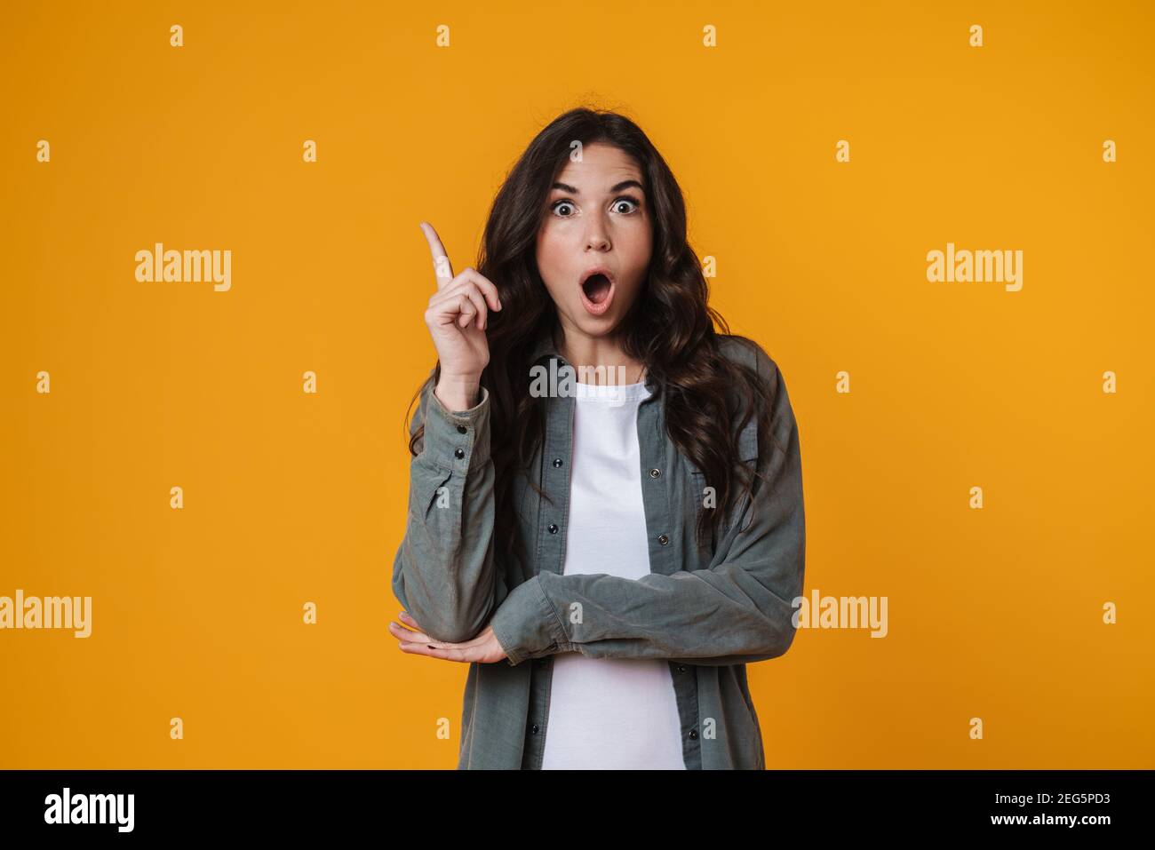 Shocked beautiful girl exclaiming and pointing finger upward isolated ...