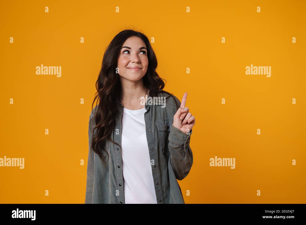 Cheerful beautiful girl smiling and pointing finger upward isolated ...
