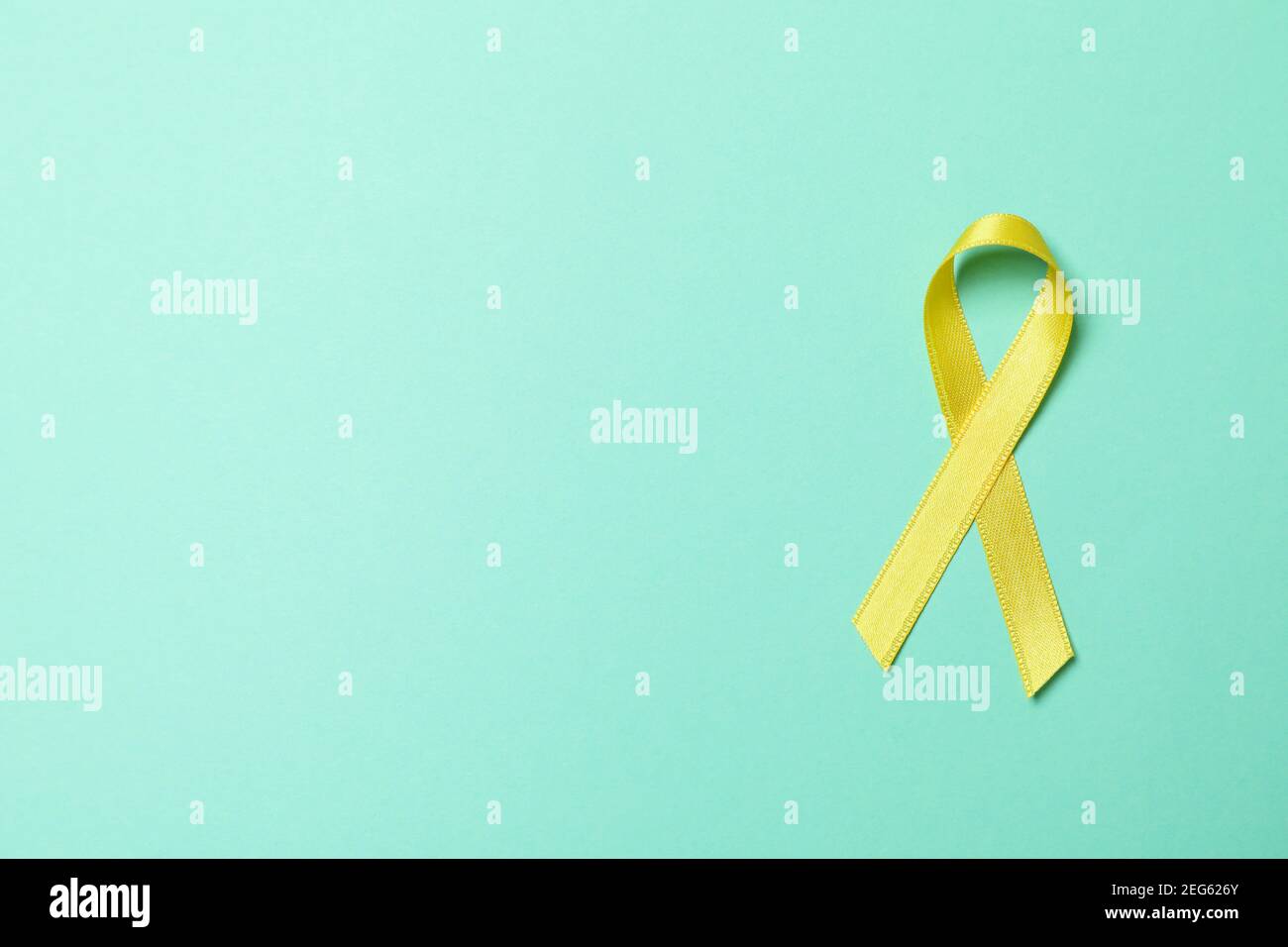 Childhood cancer awareness ribbon on mint background Stock Photo