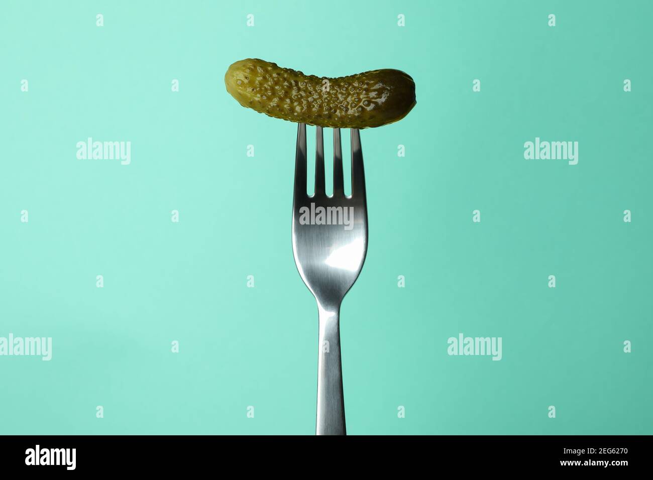 Fork with pickled cucumber on mint background Stock Photo