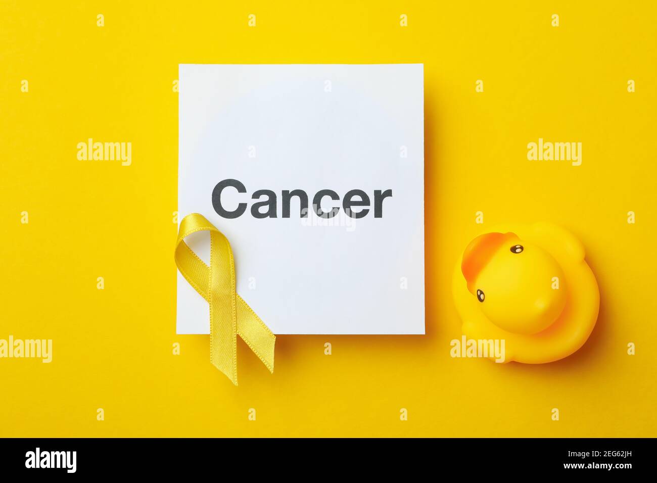 Text cancer, awareness ribbon and rubber duck on yellow background Stock Photo