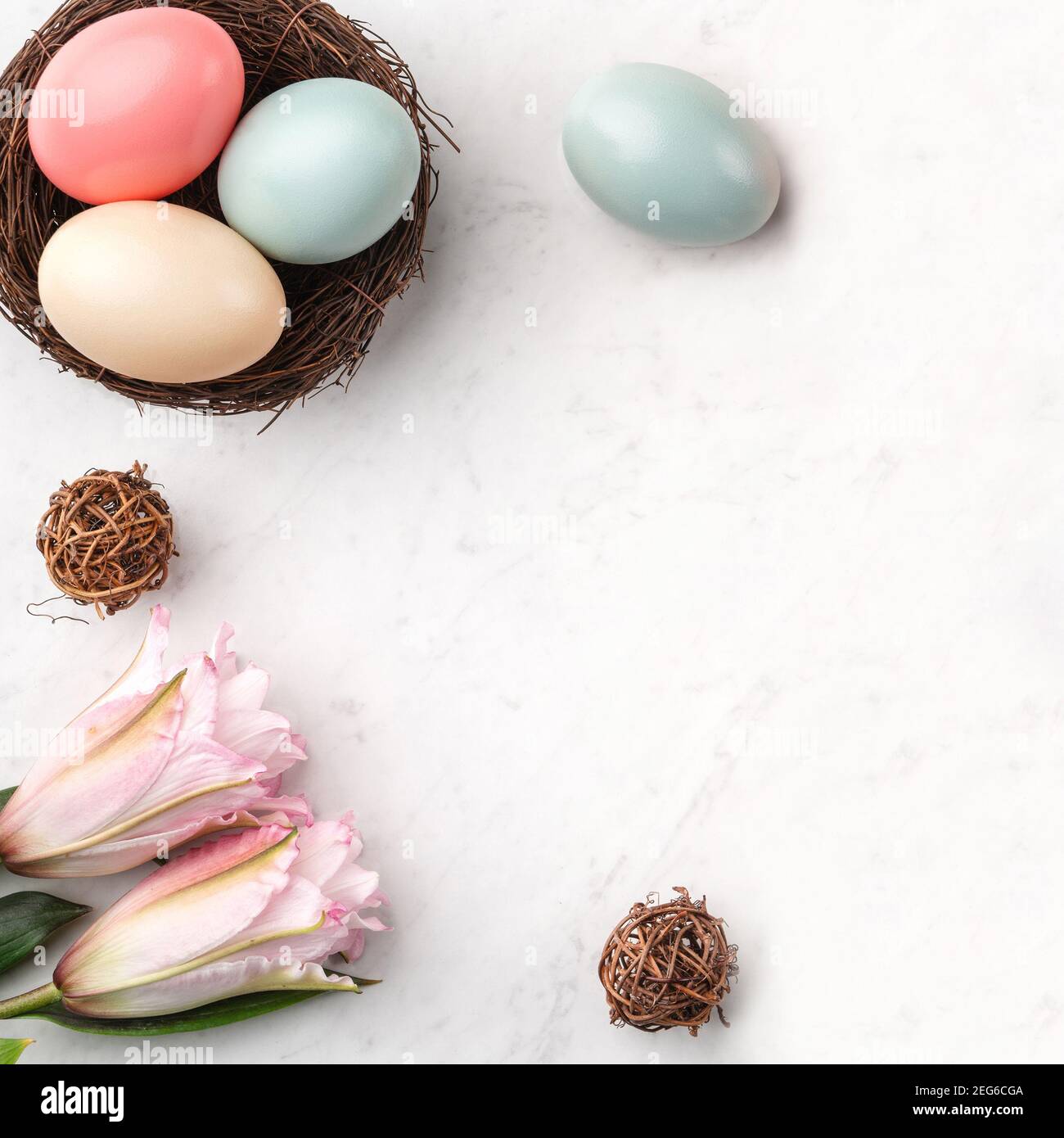 Colorful Easter eggs in the nest with pink lily flower on bright marble ...