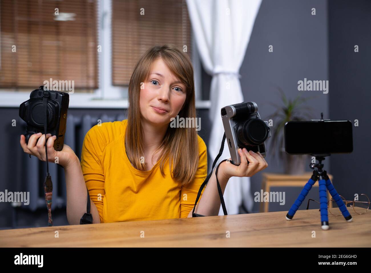 Influencer holding two photo camera. Vlogger, taking about her 
