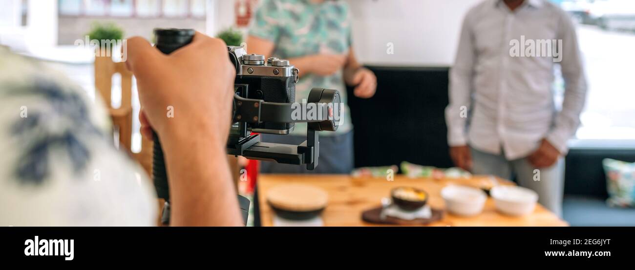 Unrecognizable camera operator recording cooking workshop. Selective focus on camera in foreground Stock Photo