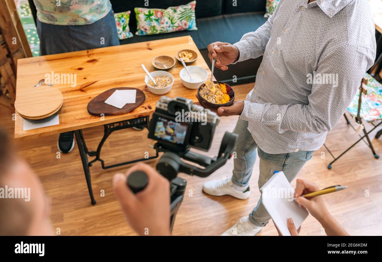 Unrecognizable camera operator recording a streaming cooking tutorial. Selective focus on breakfast bowl in background Stock Photo