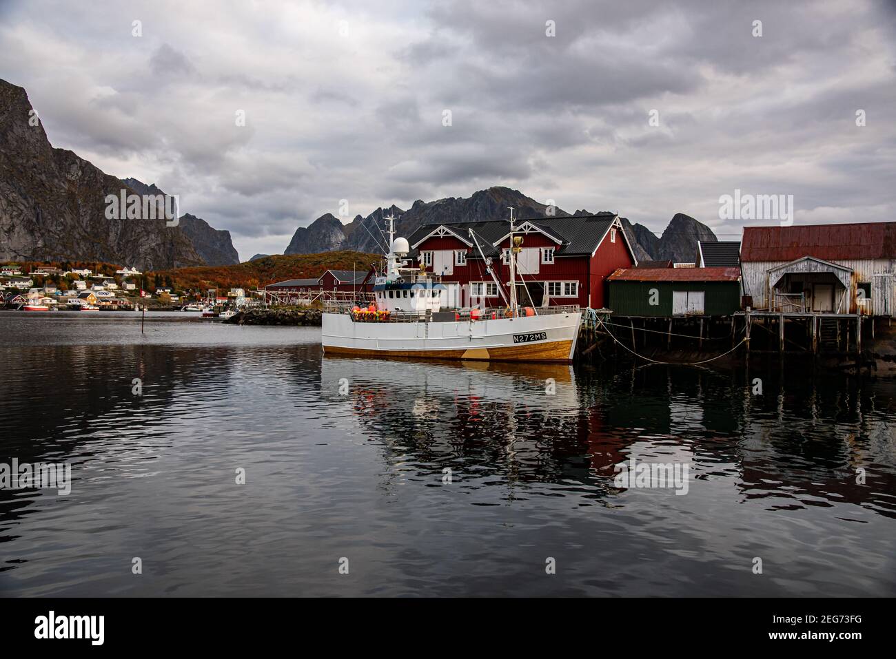 Typical Norwegian fishing village with traditional red rorbu huts, Reine, Lofoten Islands, Norway - fischer mole for boats in the background - the eve Stock Photo
