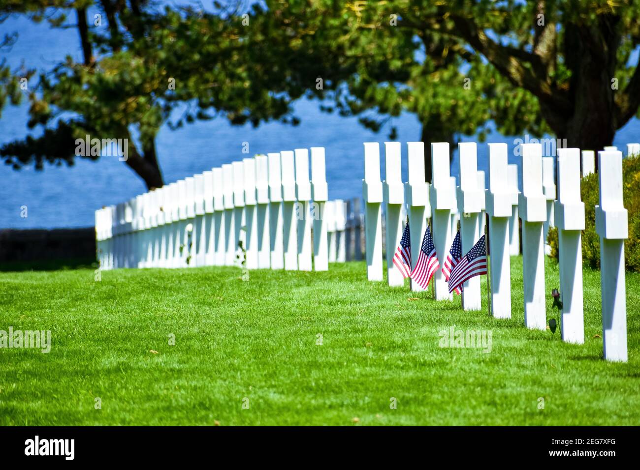 NORMANDY, FRANCE - July 5, 2017: Detail of headstones with cross and American flags in the American Cemetery of the Battle of the Normandy Landings du Stock Photo