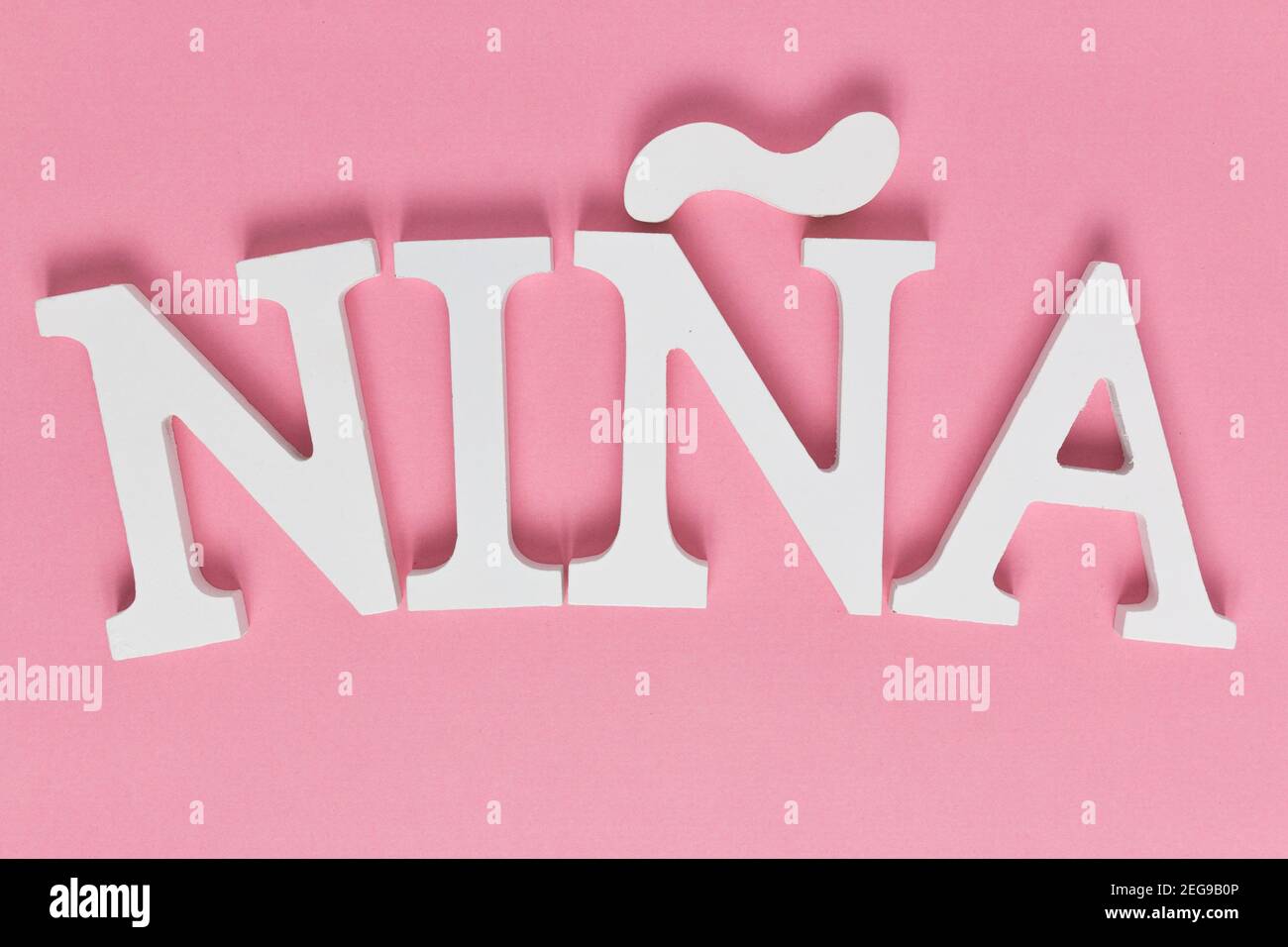 Top view of Spanish &ldquo;NINA&rdquo; writing isolated on a pink background Stock