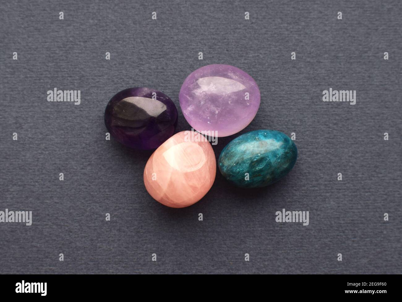 Multi-colored gemstones, cut tumbling stones. Amethyst, rose quartz, apatite  on a gray background. Stock Photo
