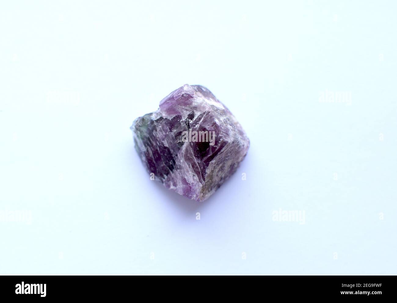 Natural rough purple fluorite crystal on white background. Stock Photo