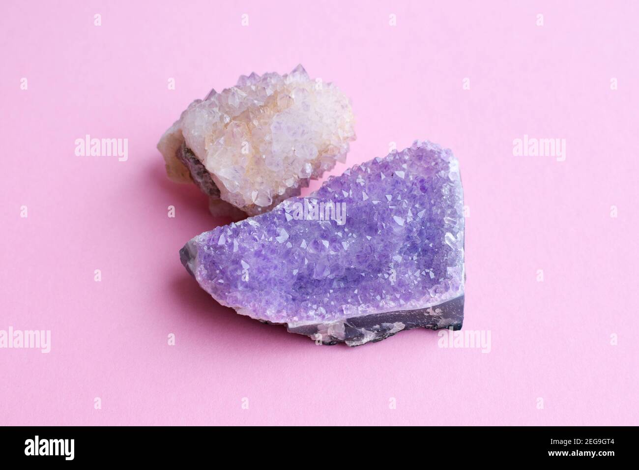 Beautiful druse of natural purple mineral amethyst and cactus amethyst crystal on a pink background. Large crystals of precious stones. Stock Photo