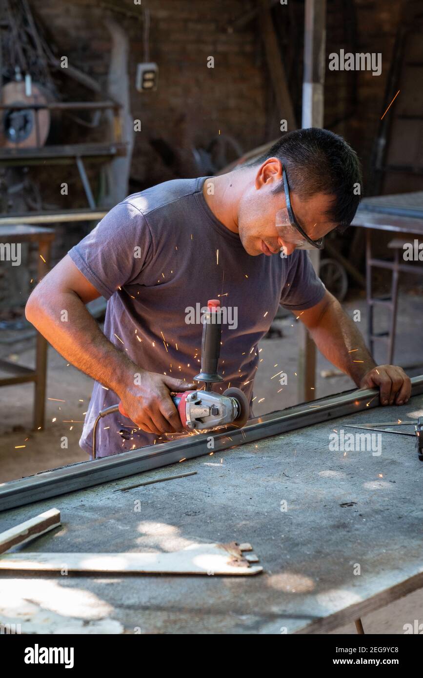 a man working cutting metal bar with a circular electric tool that ...