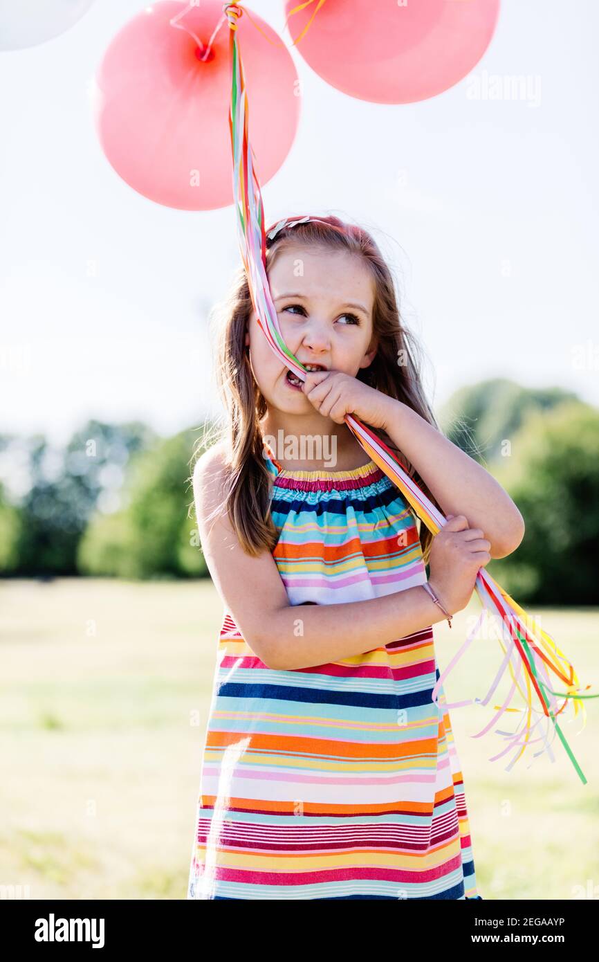 https://c8.alamy.com/comp/2EGAAYP/little-girl-chewing-balloon-strings-in-her-mouth-outdoor-childhood-activities-2EGAAYP.jpg