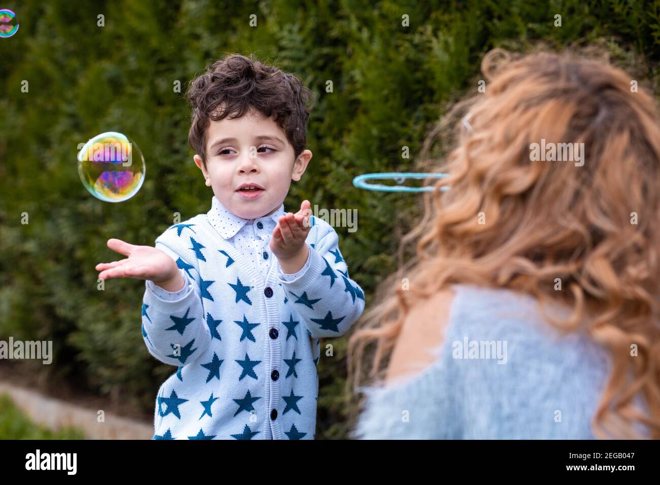 Mom playing with her little boy outdoors. Making soap bubbles with bubbles stick Stock Photo