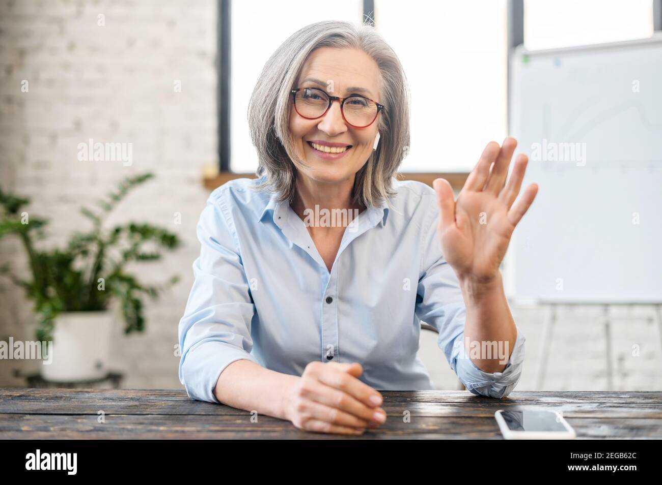 Video chat with a smiling senior elderly business woman. Webcam view of  charming aged coworker, mature female colleague waving into camera,  greeting Stock Photo - Alamy
