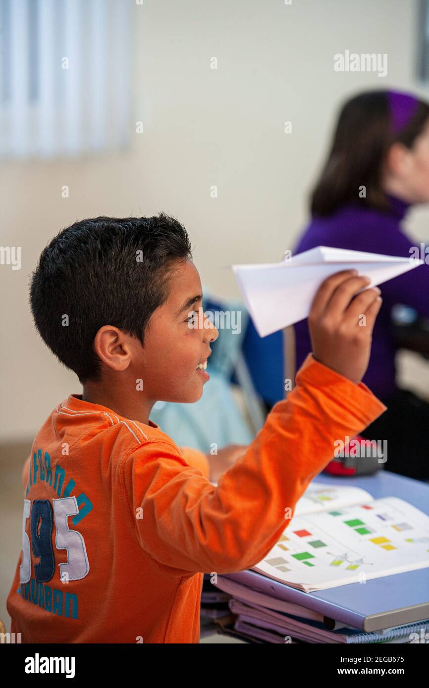Young boy misbehaving with paper airplane in a school classroom Stock Photo