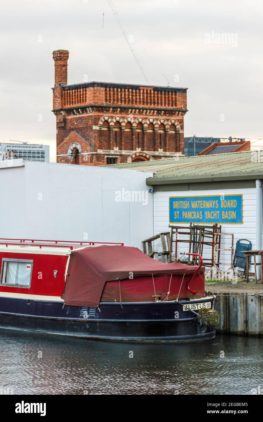 A red narrowboat moored in the St. Pancras yacht basin, the Victorian water tower in the background, King's Cross, London, UK Stock Photo