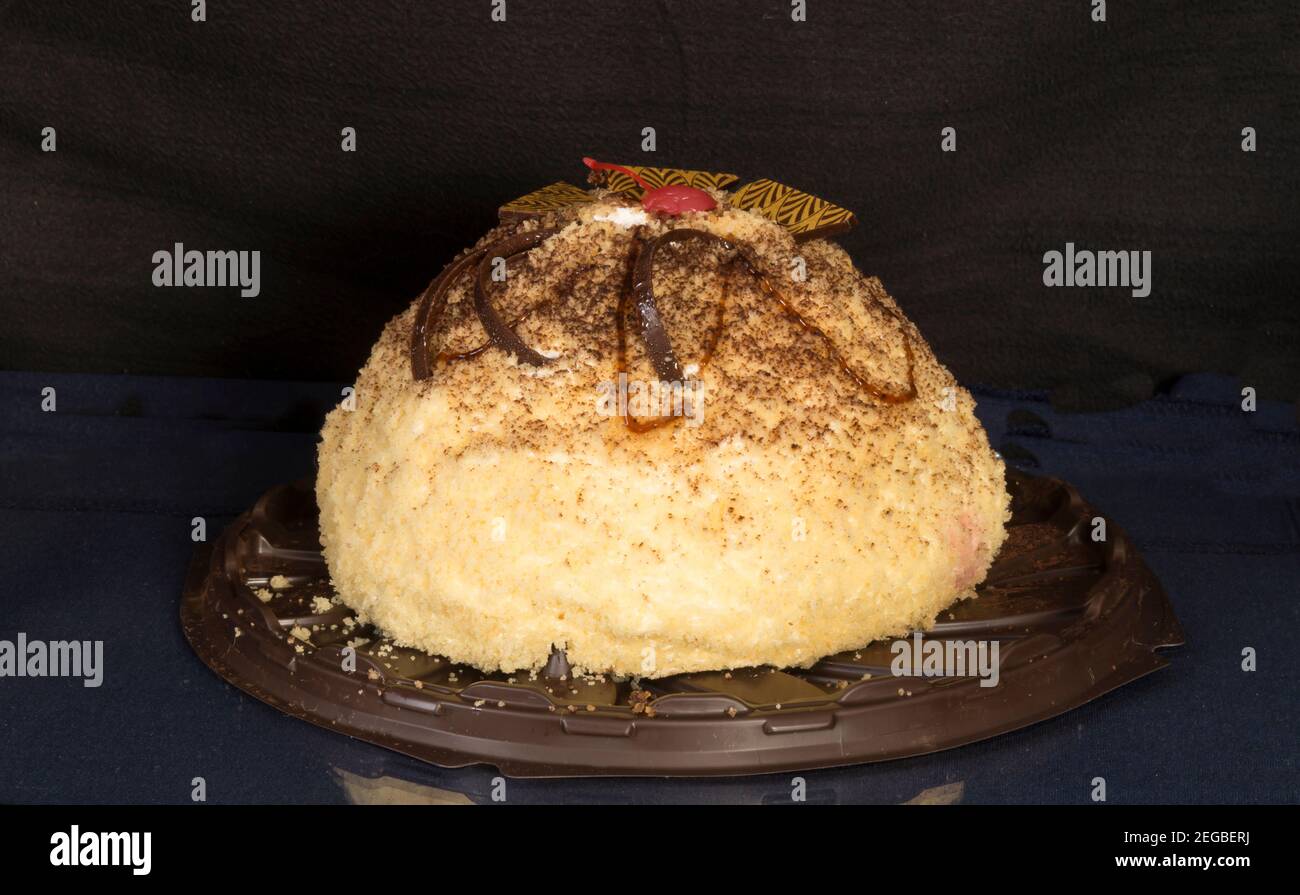 A sweet cake stands on a glass table with a reflection. Food on a black background Stock Photo