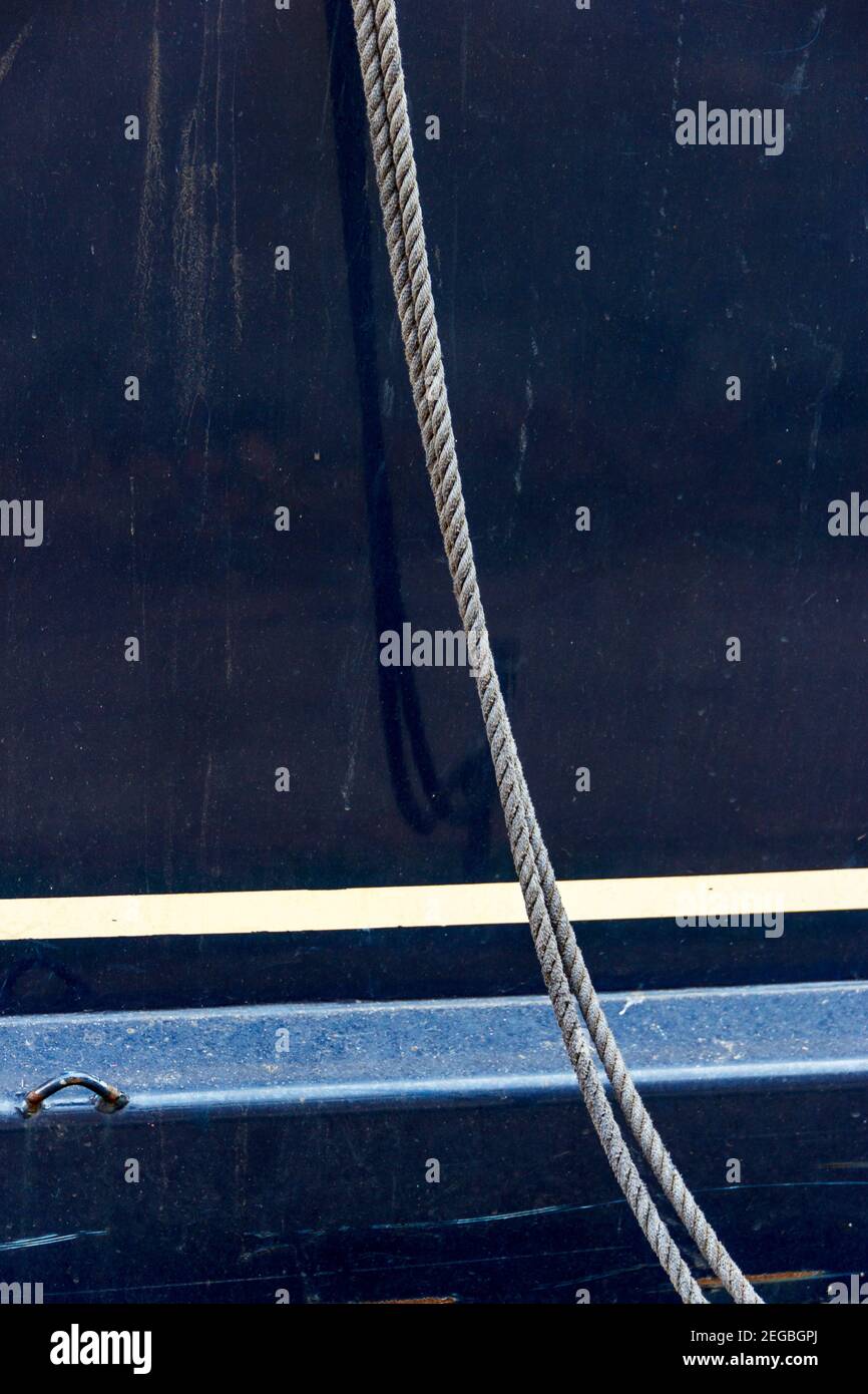 Abstract composition of a rope hanging from the side of a canal ...