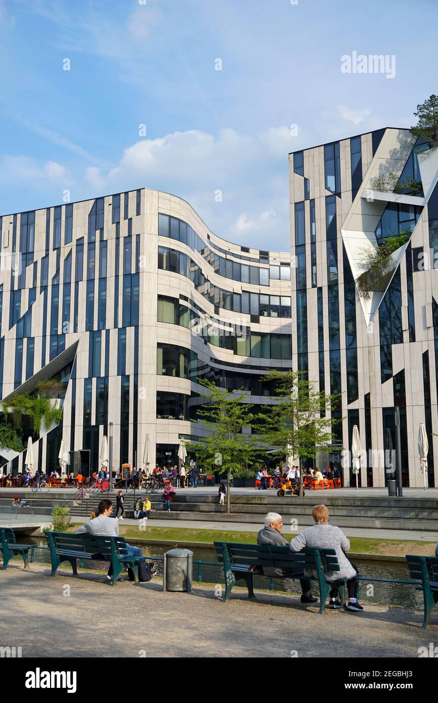 'Kö-Bogen' buildings, designed by New York star architect Daniel Libeskind, completed in 2013. People sitting on benches and enjoying the nice weather. Stock Photo