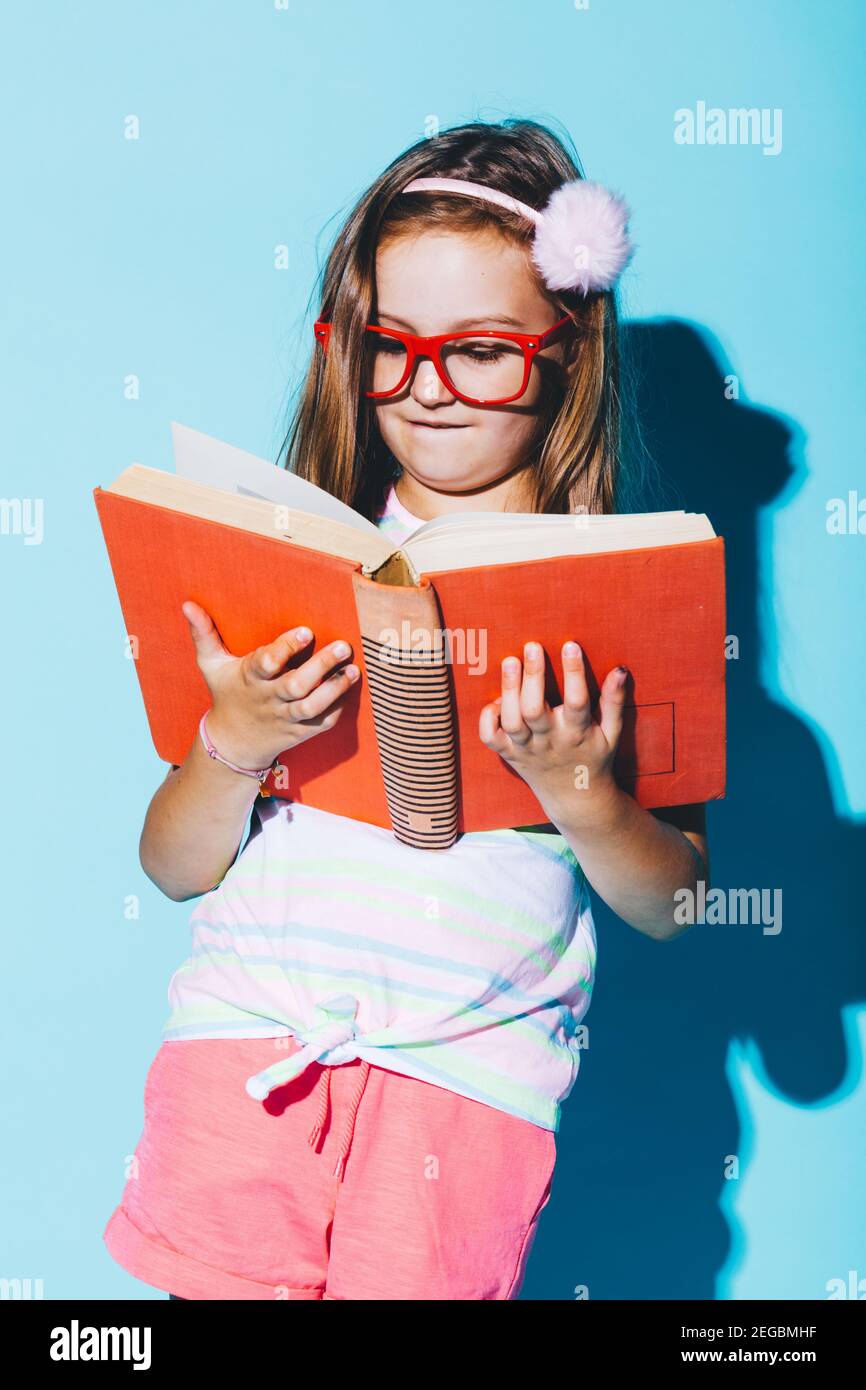 Little girl reading a book, wearing funny red glasses. Blue background. Funny portrait. Child nerd Stock Photo - Alamy Little girl reading a book, wearing funny red glasses. Blue background. Funny portrait. Child nerd Stock Photo - Alamy