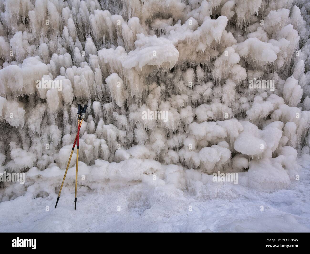 Hiking sticks by an ice wall. Strongly structured and artistic structures made of ice, icicles. Wanderstöcke an eine Wand aus Eis gelehnt. Eiszapfen Stock Photo