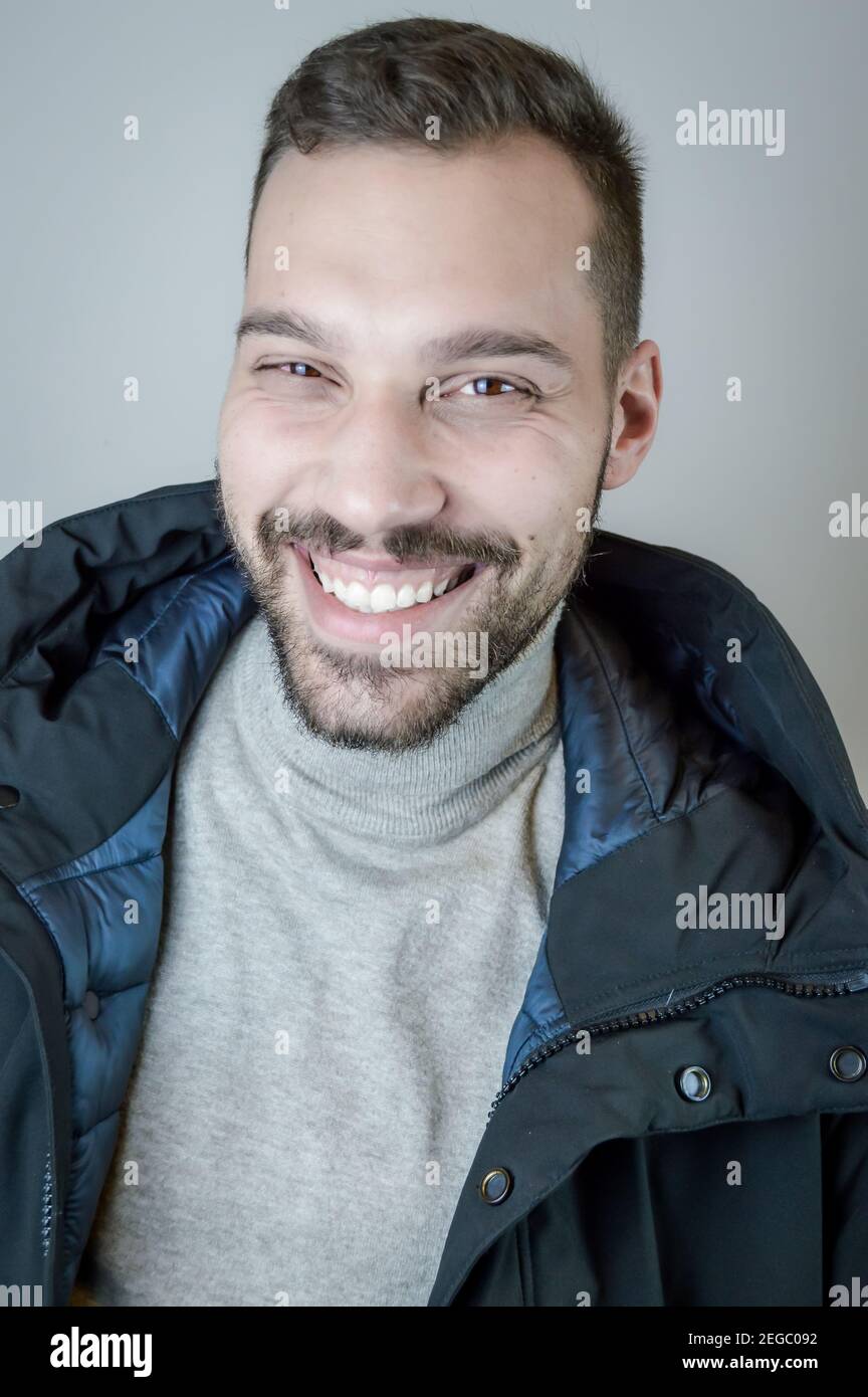 Young man with a short beard laughs cheerfully during a conversation Stock Photo