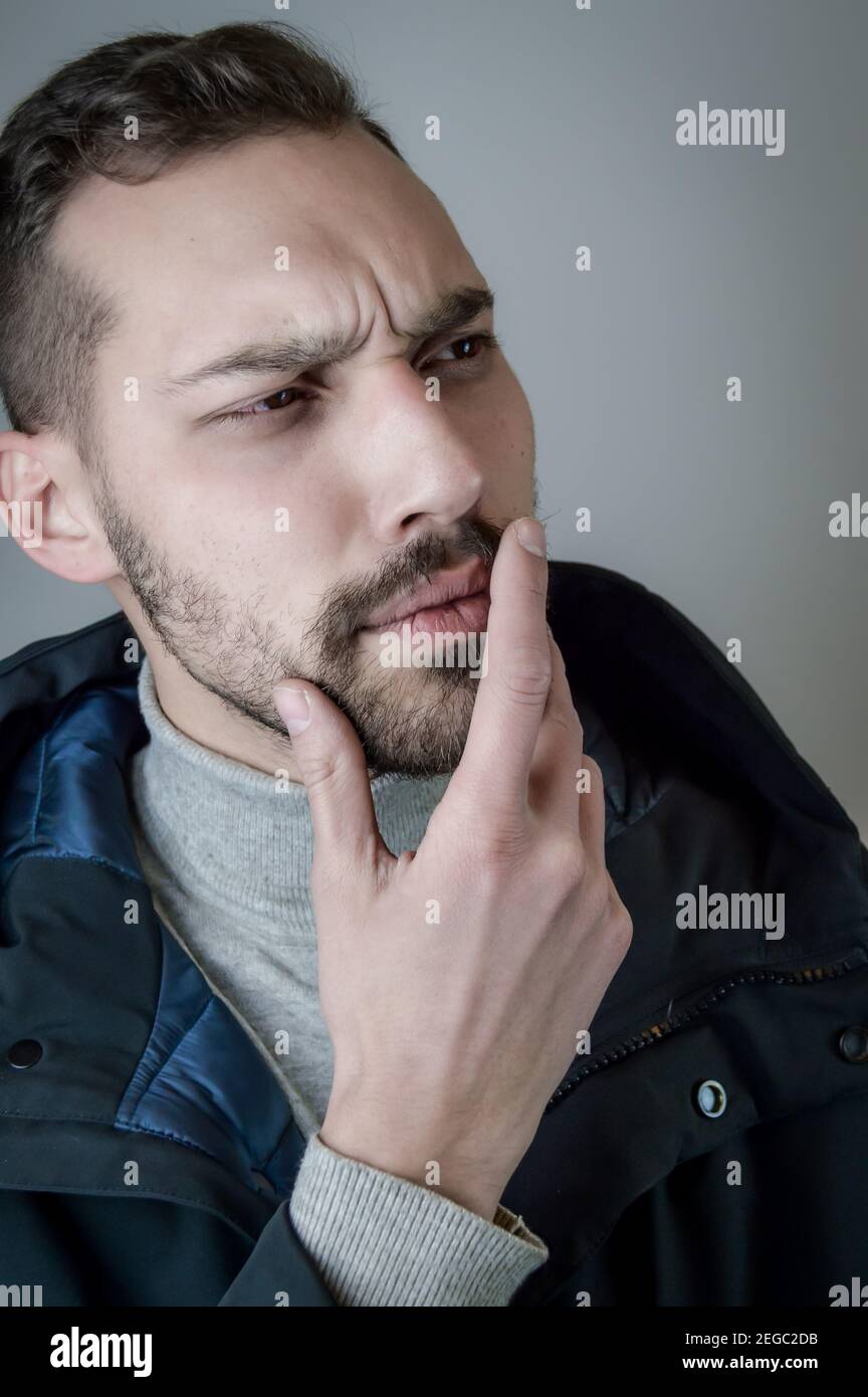 Portrait of a young man touching his chin in a moment of doubt or reflection Stock Photo